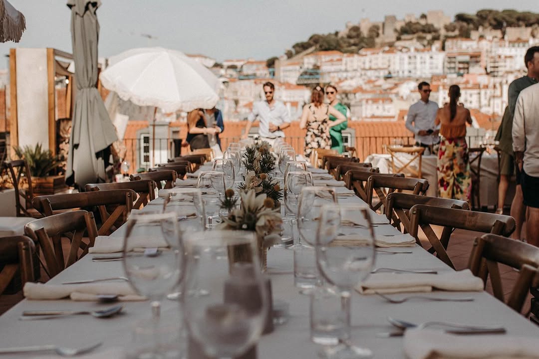 A long table set for a private gathering on The Art Inn rooftop, with São Jorge Castle beyond